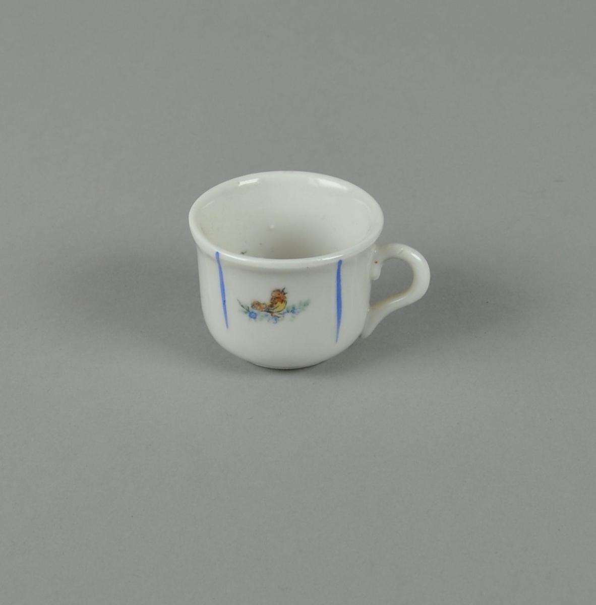 Hvit kopp av glassert keramikk, med malt dekor av nedovergående blå striper og fugl i midten.
