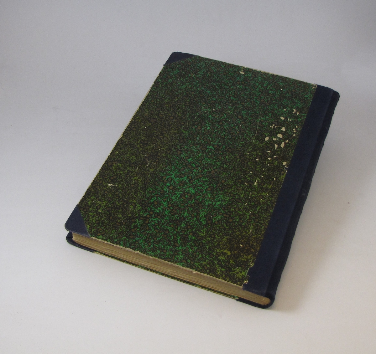 Bok med grønt papiromslag og blå tekstilrygg, på framsiden er det et klistermerke med påskrift. Boken inneholder avisutklipp fra perioden mellom 1946 og 1957.