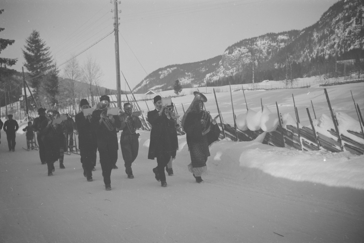 På veg til kostymehopprenn i Veistensbakken i 1950, arrangert av Vestre Gausdal musikkforening. I bakgrunnen på venstre side skimtes Haugetun i Forsetgrenda, Vestre Gausdal