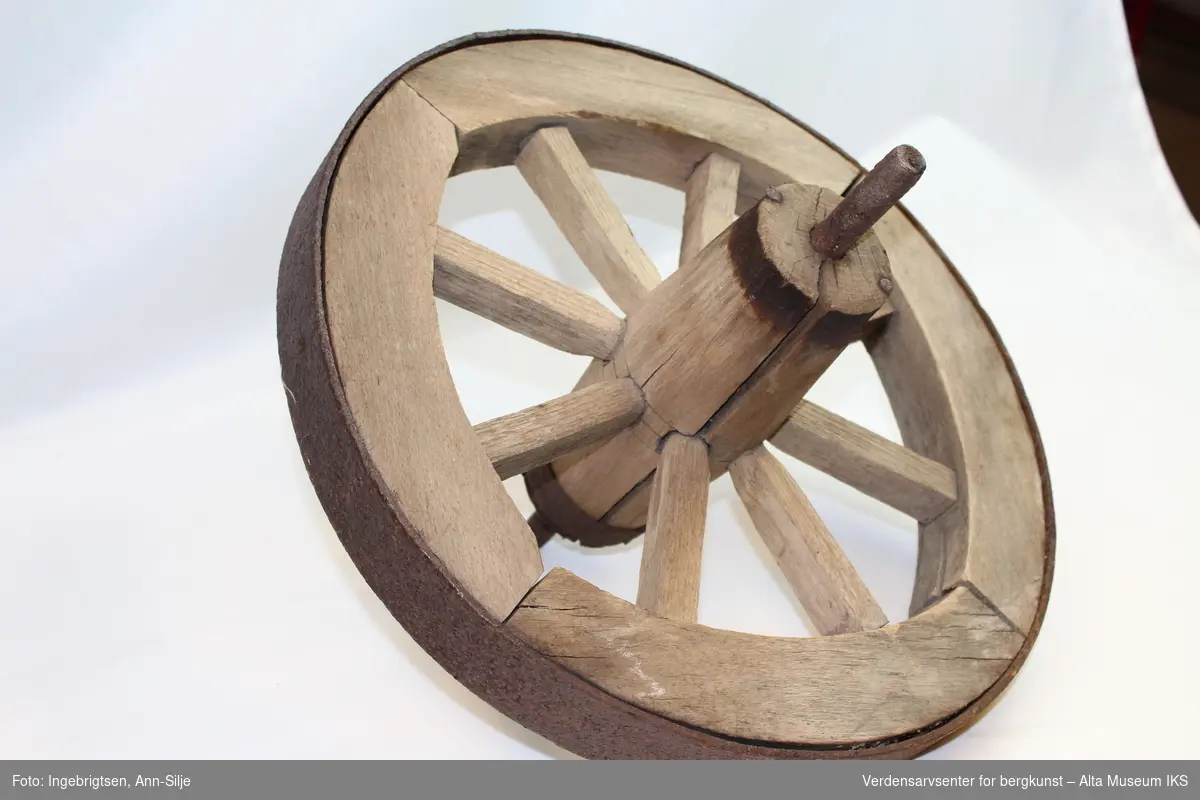 Hjul av tre med jernbeslag.
Form: 4 tredeler i hjulgang, 8 eiker og treaksling med jernbeslag.