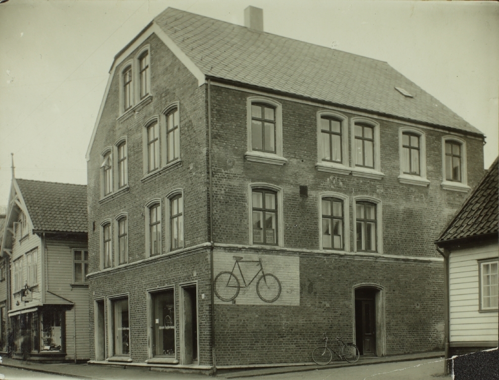 Mursteinsbygning Langgata 6, den første sykkelfabrikken til Jonas Øglænd Sandnes, i vinduet står Øglænds cycleforretning.