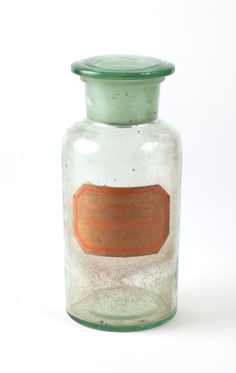 Standglass med slepet glasskork til oppbevaring av pulver i laboratoriet. Gul etikett med rød ramme og giftkors.
