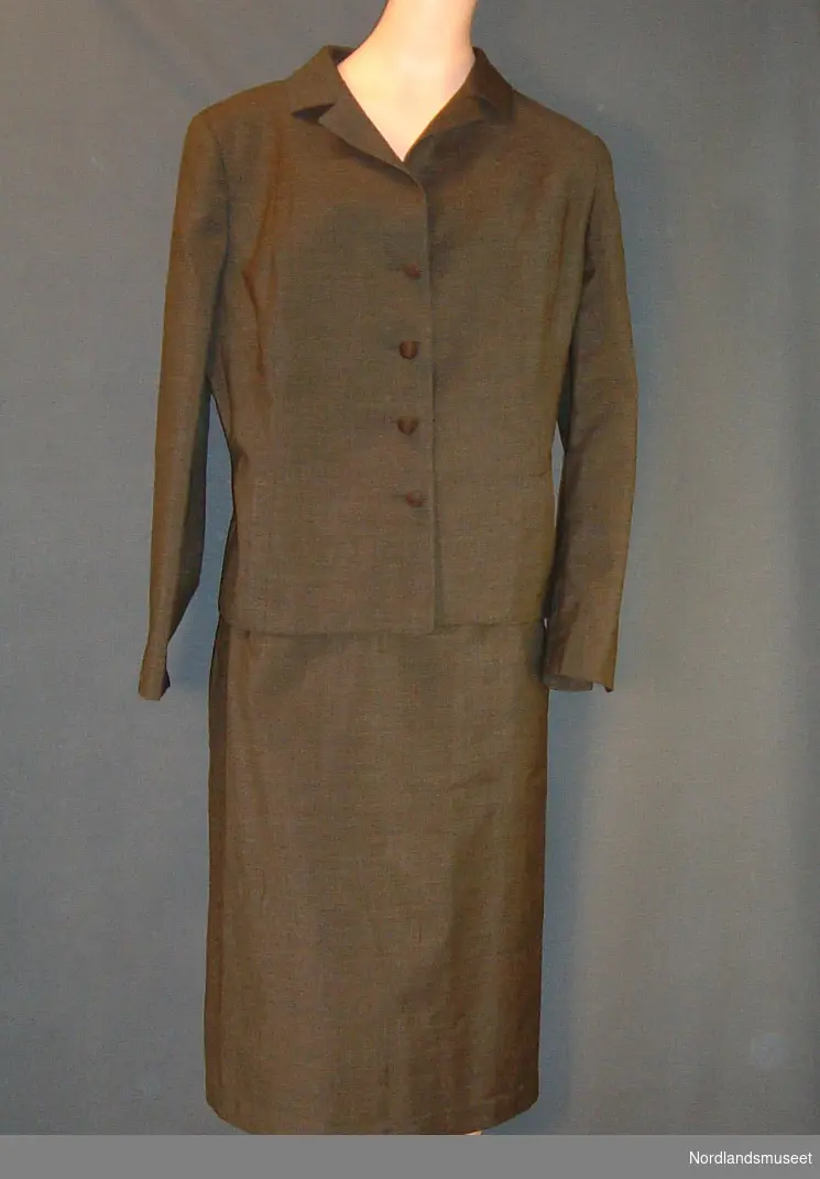 Form: kort jakke med lommer og knapper. Smalt knesitt skjørt.
