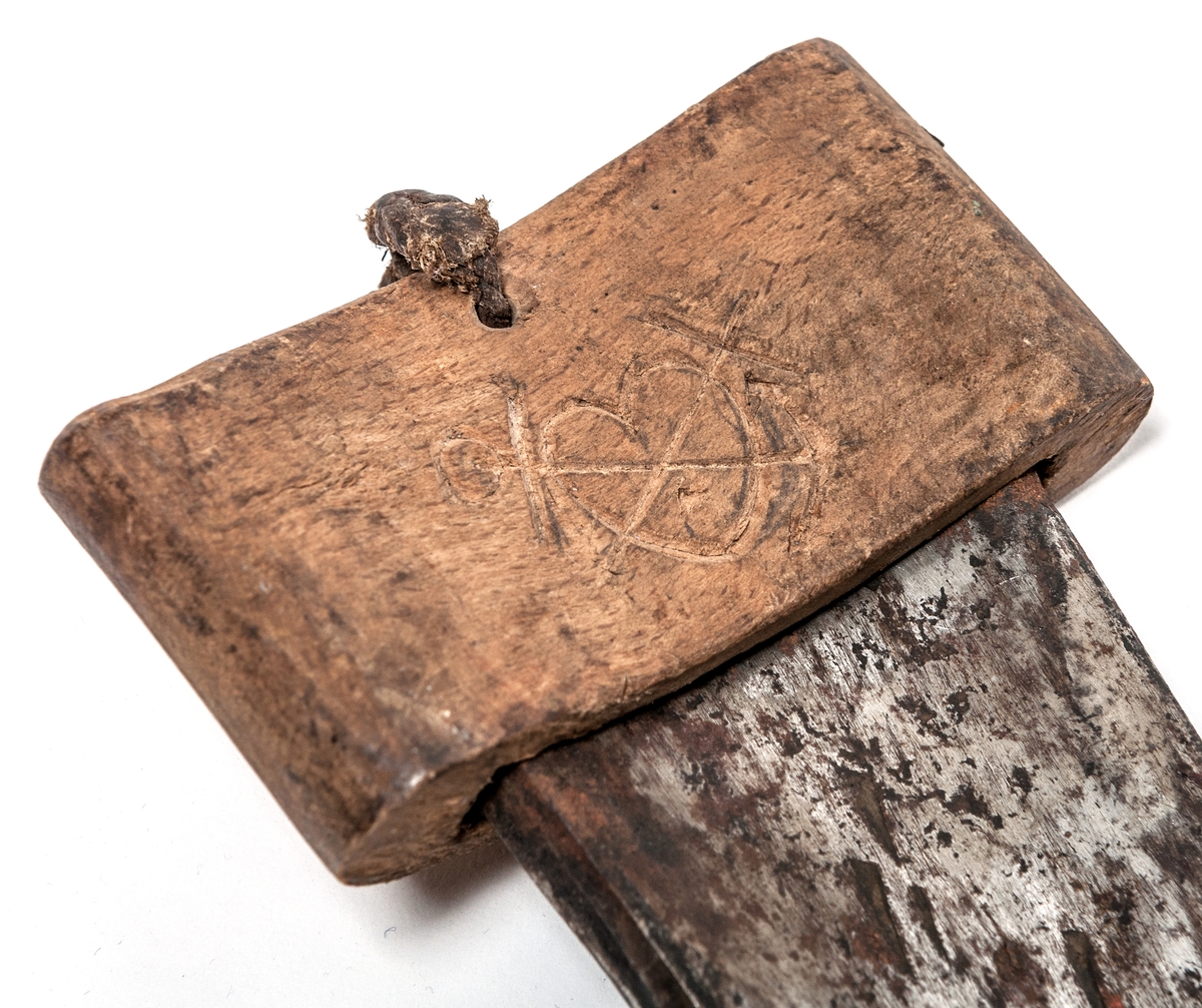 Håljärn med svarvat trähandtag. Eggskydd av trä, märkt med monogram och 
ÅR 1880
10.M5M
11.DT0

Samt symboler för tro, hopp och kärlek.