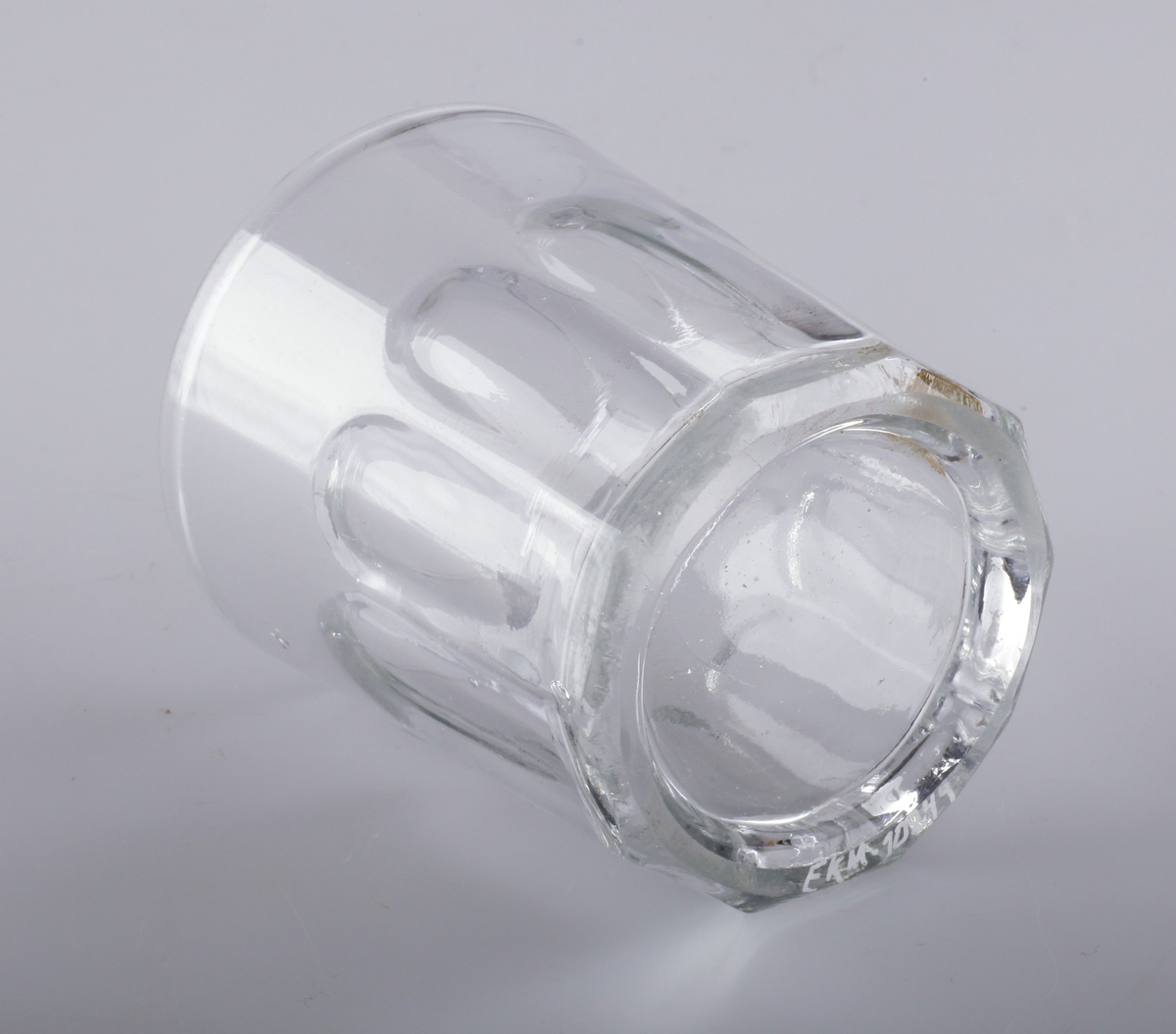 Munnblåst glass, blåst i form med flater som skal illudere slipning. Glasset er tykt og har mange ujevnheter og bobler i glassmassen. Bunnringen er slipt, slik at glasset står plant.