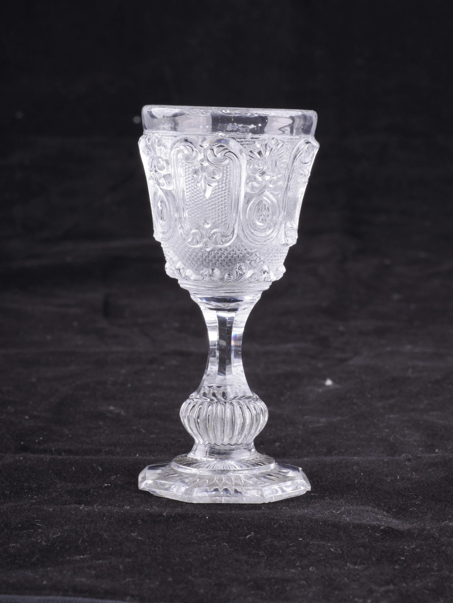 Drammeglass i pressglass, med slipt stett og fotplate. Samme mønster som karaffelen nr EKM-10257.