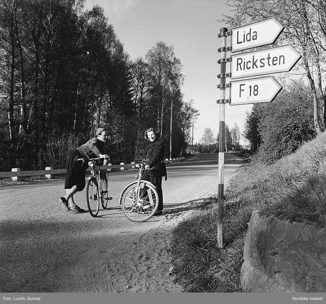 Två cyklister står på en väg i Tullinge, Södermanland, år 1952.