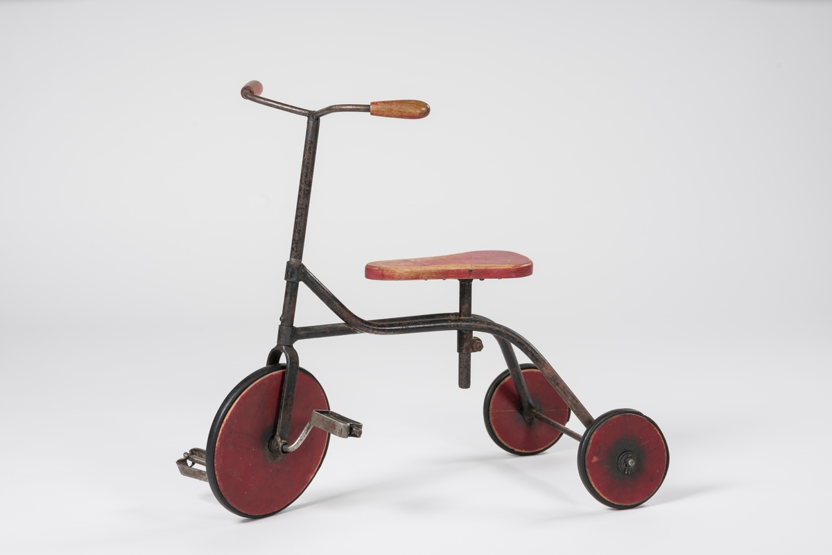 Form: Ramme av hulrør, forhjul med pedaler, flatt, innsvinget sete.
