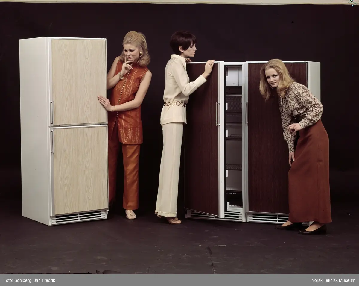 Reklamefoto for kjøleskap. Tre unge kvinner kikker på to kjøleskap / kombiskap.