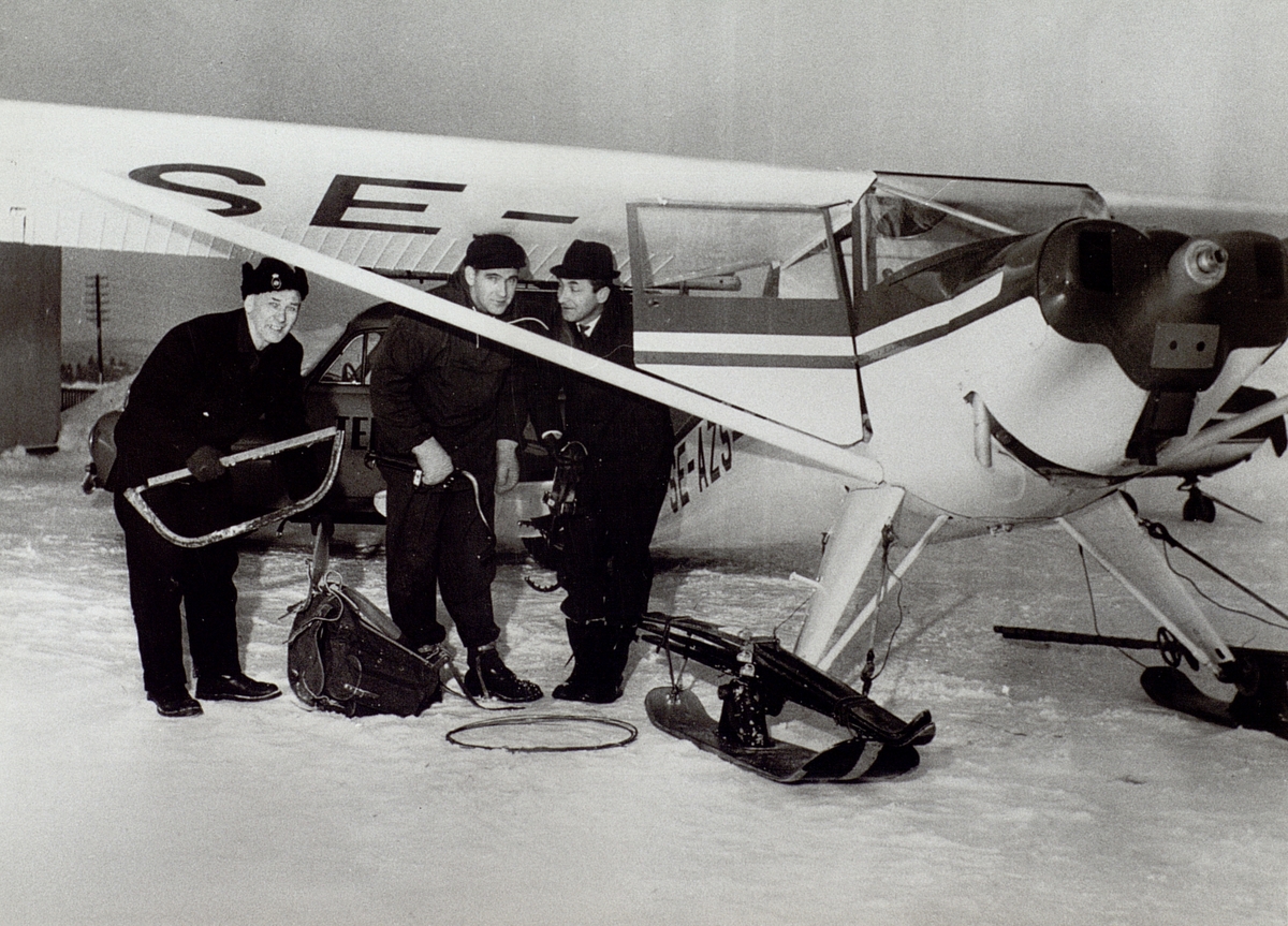 Motlanda flygfält 1966. Från vänster, Erik Barås, Arne Sandström och Arne Kring. Med detta flygplan åkte man ut och reparerade telefonlinjerna till Kråkön och Agön. Det var första gången som man i Hudiksvall fick ta flygplan till hjälp vid felavhjälpning.