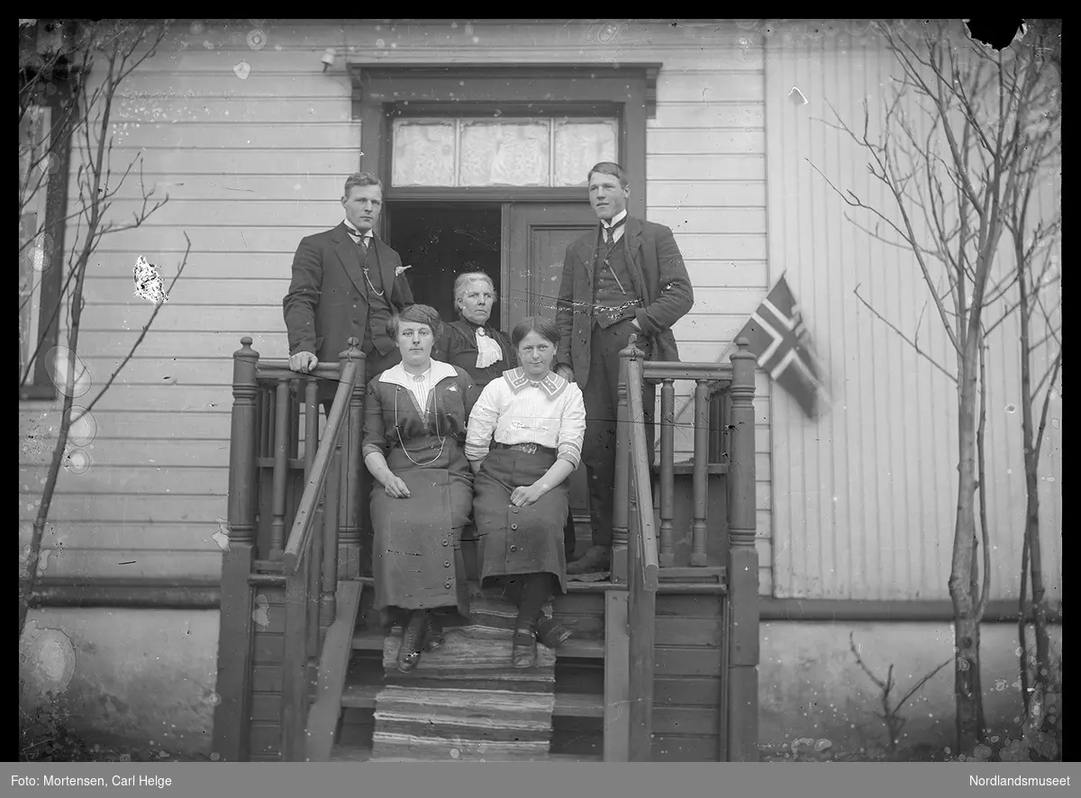 En eldre kvinne og fire unge voksne på hustrappen.