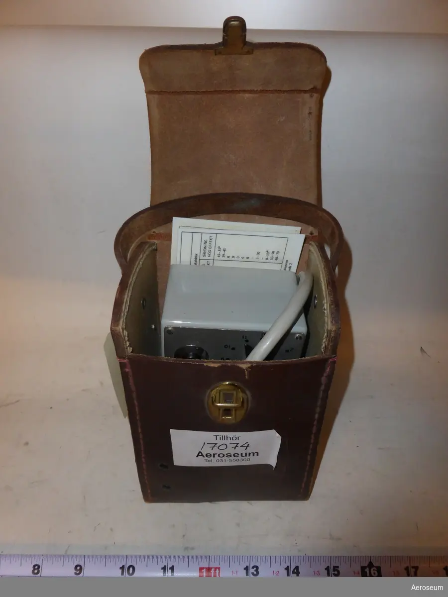 En Kontrollbox i brun läderväska, tillsammans med 2 mättabeller. Till för RA 800. I väskans läder är Tre kronor inpressat och i kontrollboxen sitter det fast en grå sladd.