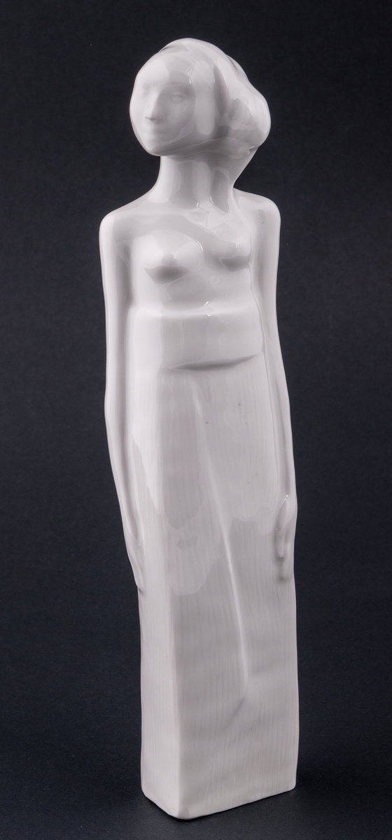 Figurin, föreställande en kvinna. Vit glasyr. Saknar stämplar och signatur. Okänd formgivare. Oklar tillverkare.