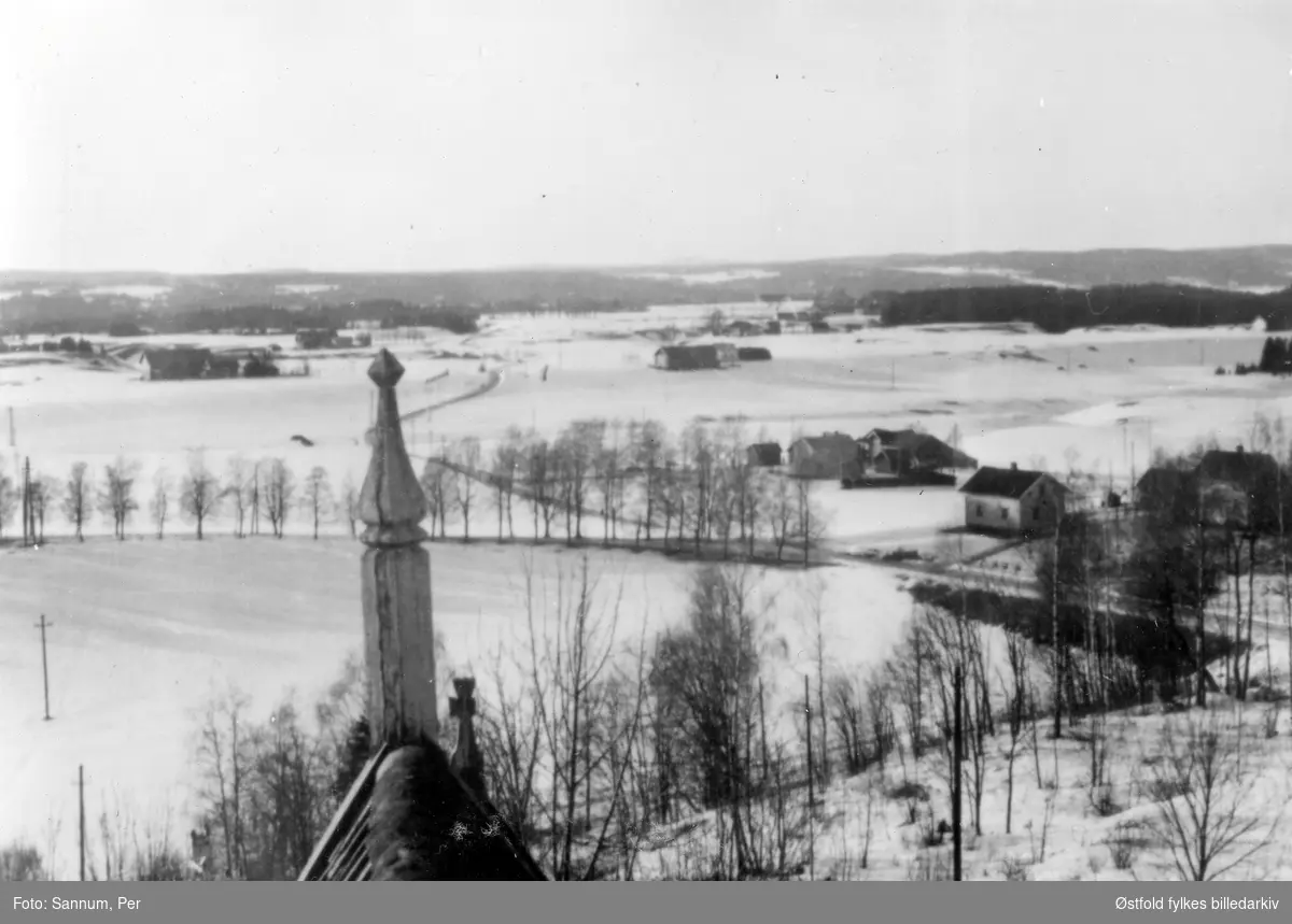 Kirkebygda i vinterdrakt sett fra klokketårnet i Trøgstad kirke ca. 1950.