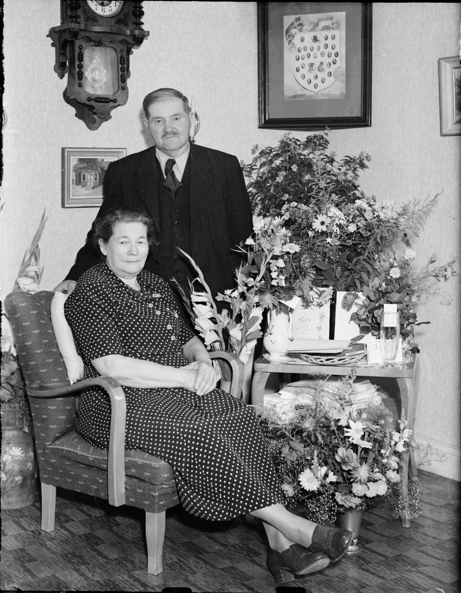Kvinna och man i hemmiljö omgiven av blommor, Östhammar, Uppland,