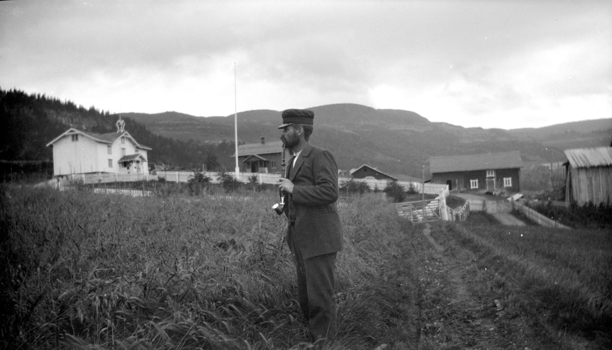 Mann med krokpipe frem en gård, antakelig i Østre Gausdal