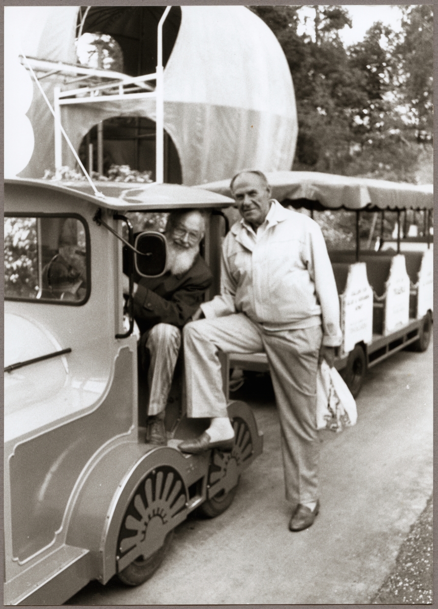 Sven-Erik Berglund med skägget, motorvagnsförare och Walter Nilsson, trafikbiträde provar minitåget i Parken Zoo på Trafikaktiebolaget Grängesberg - Oxelösunds Järnvägar, TGOJ:s pensionärsträff i Eskilstuna 1989.
