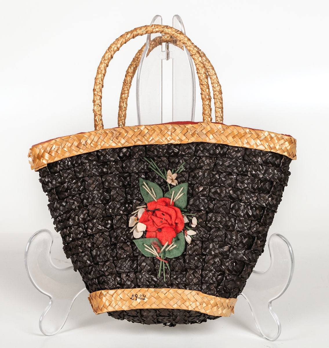 Handväska i form av en flätad korg, rött tygfoder, påsydda blommor av ylle.