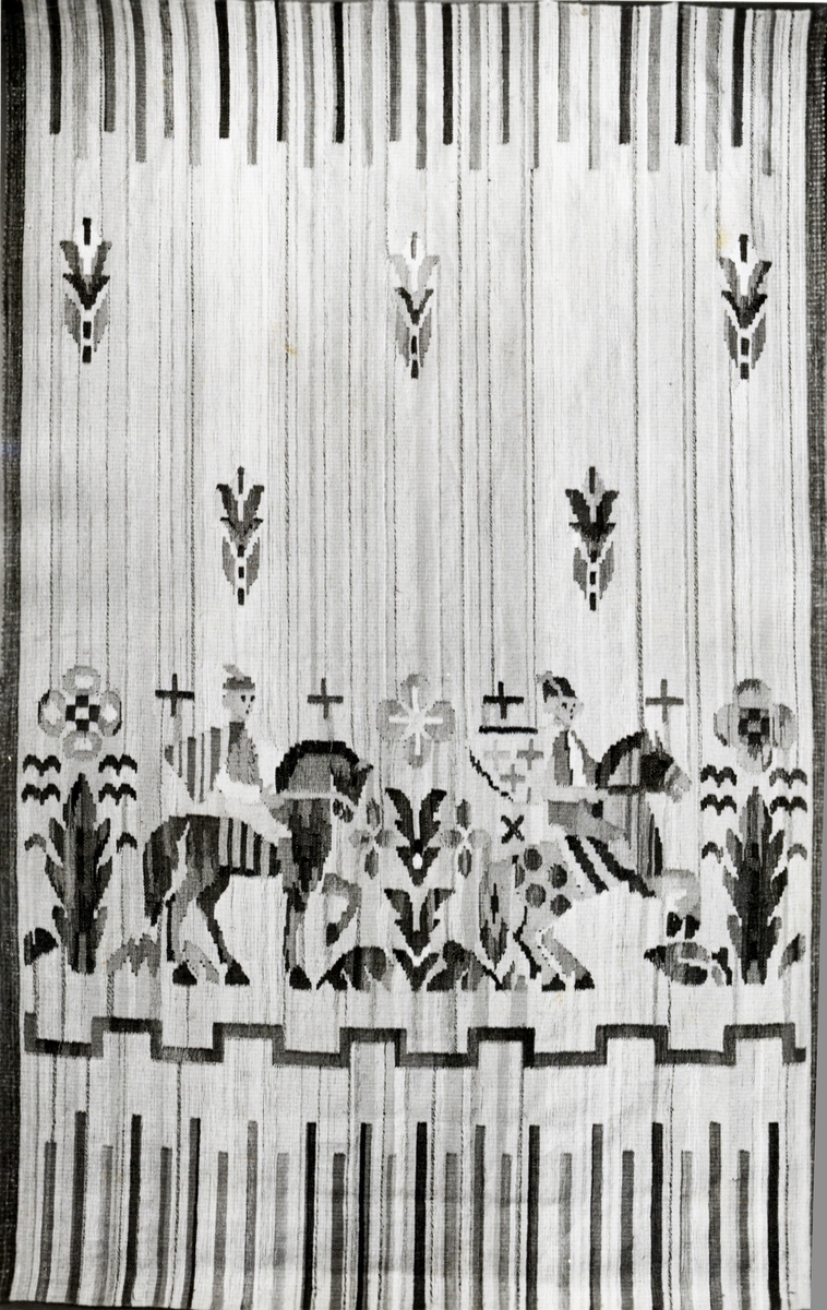 Foto (svart/vitt) av en bonad i linneväv, med motiv av hästar med ryttare m.m.
Inskrivet i huvudbok 1983.