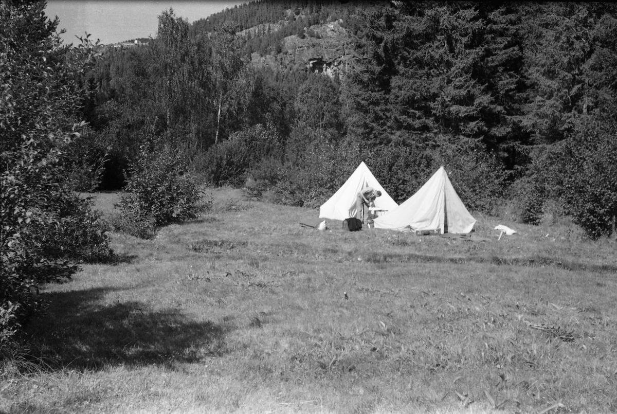 Tre avfotograferte bilder av to telt slått oppp på ei grasslette ved en bekk. En uidentifisert mann står ved teltene på to av bildene. Stedet er heller ikke identifisert.