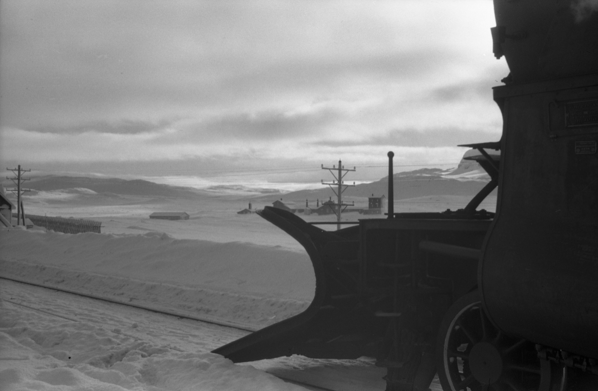 Avfotografert bilde fra jernbane, trolig Bergensbanen, I forgrunnen trolig fronten på et lokomotiv med snøplog.