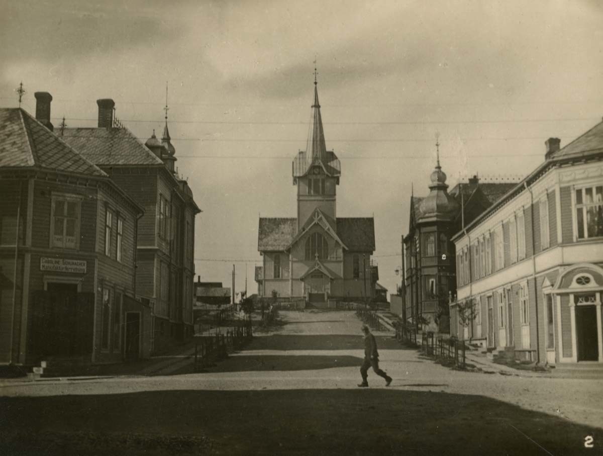 Kirkegata i Hammerfest før ødeleggelsene under andre verdenskrig. Blikket er rettet oppover bakken, mot kirka. En person kryssen veien.