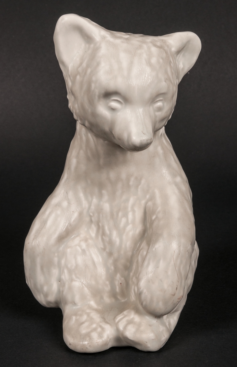 Figurinen Pumsi, föreställande en sittande björn. Flintgods med gråvit glasyr. Formgiven av Lillemor Mannerheim 1955.
