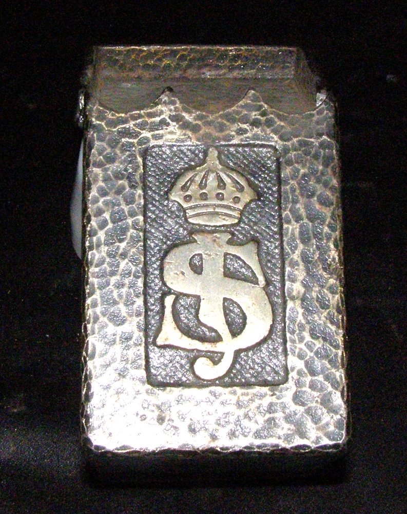 Askkopp av guldfärgat metall med ungefärlig form av en postlåda. Dekorerat med krönt SJ-symbol.