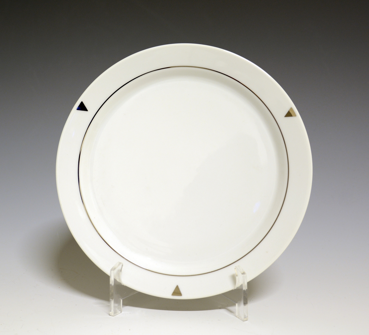 Asjett av porselen. Hvit glasur, med platinastrek innerst på fanen. Tre trekanter i platina peker mot speilen.

Modell: Style, formgitt av Poul Jensen.