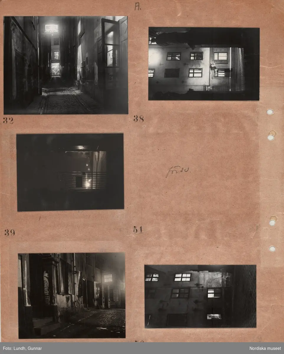 Motiv: (ingen anteckning) ;
Nattbild av stad med gator och byggnader möjligen Gamla Stan, husfasader med upplysta fönster, skyltfönster, skyltar "Hotell" Specerier Matvaror".