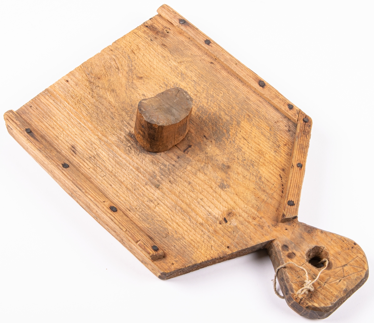 Karvbräde, skärbräda för tobak, av trä /fur eller gran/. Handtag i ena änden, smala lister påspikade utmed kanterna, samt i mitten en träkubbe islagen.