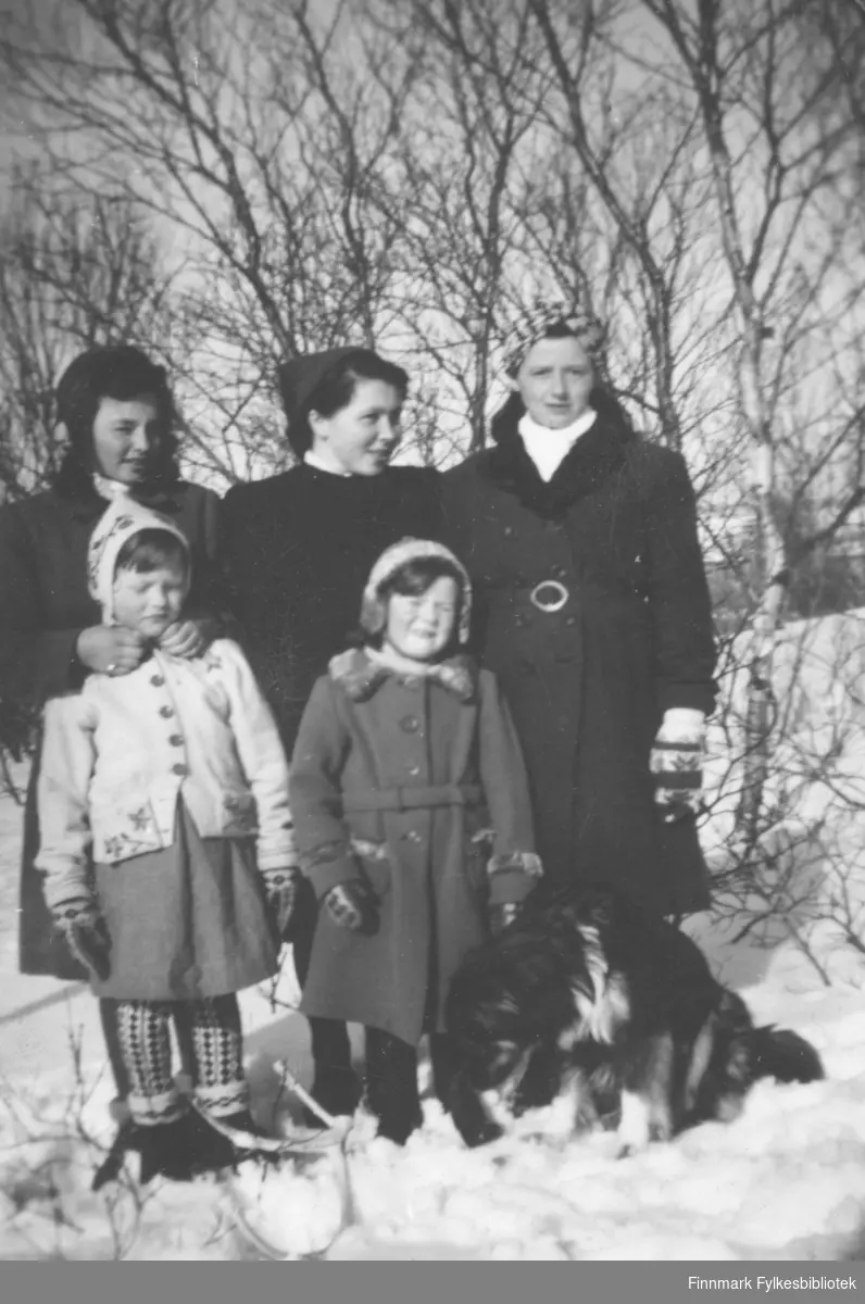 Tre kvinner, to barn og en hund fotografert ute i det snødekte terrenget. De er Grethe Iversen Solstad, Maila Iversen Losoa, Anne Lise Njolla. Barna er Anna Agnethe Mathisen og Ingrid Iversen.