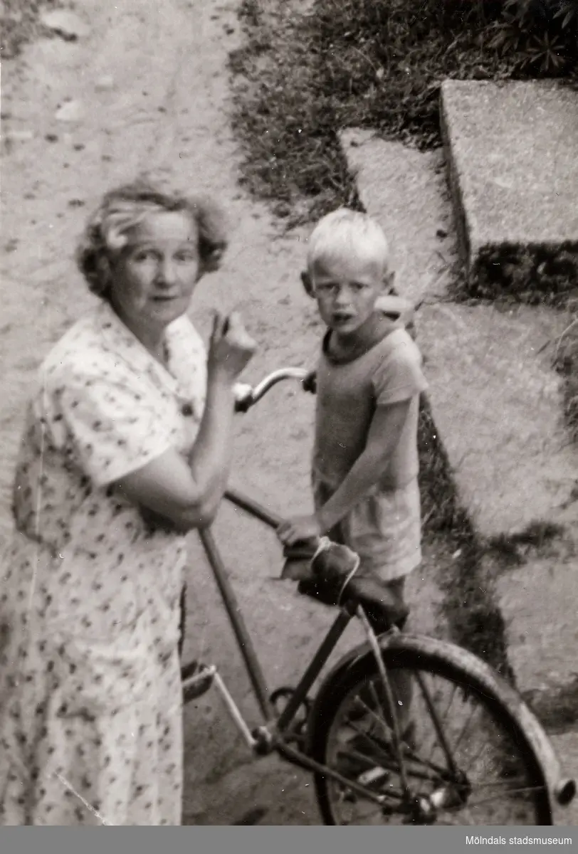 En kvinna, Silvia (okänt efternamn) och en pojke, Sven-Göran Andersson, med cykel fotograferade på gården Christinedal i östra Mölndal på 1950-talet. Gården har gett namn åt området Kristinedal och var belägen i vinkeln mellan nuvarande Rådavägen och Brovaktaregatan. År 1960 såldes gården till Fastighetsbolaget Betongblandaren (Skånska Cementgjuteriet) och revs när det nuvarande bostadsområdet anlades.