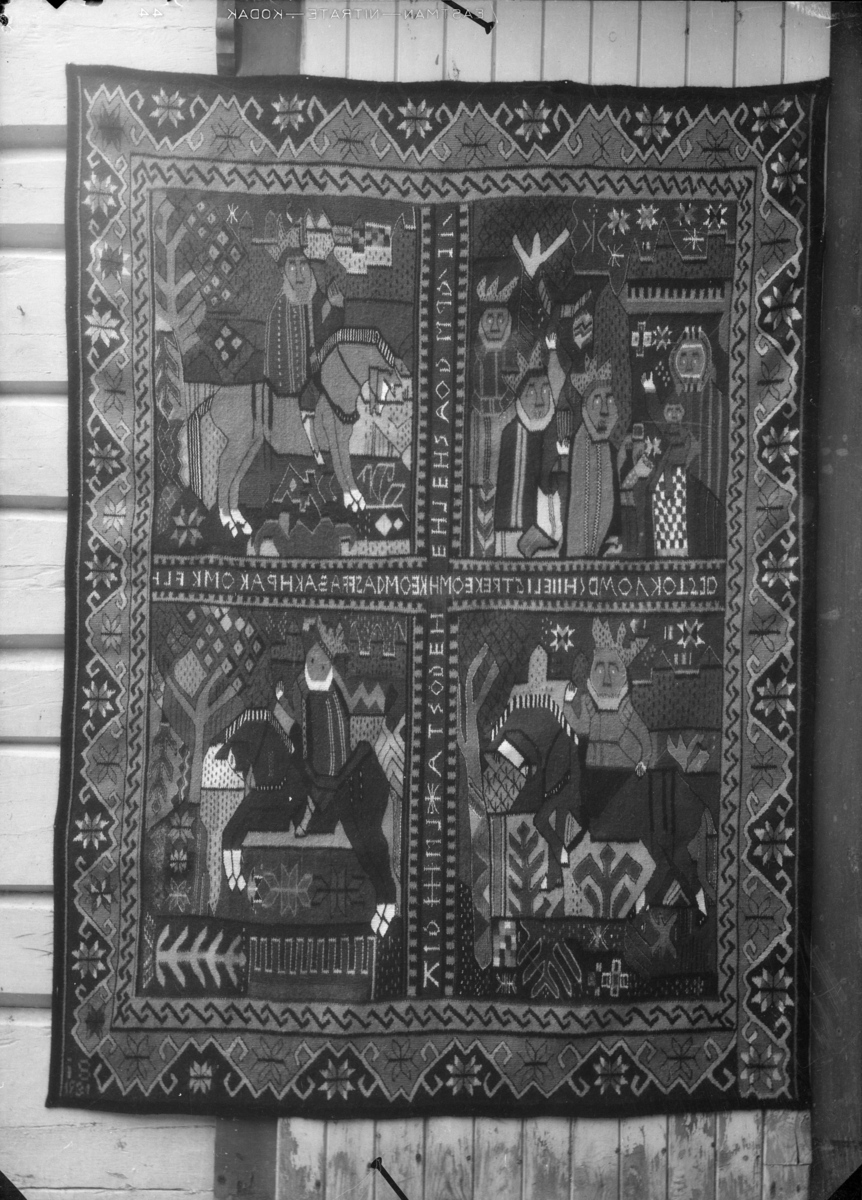 Billedvev, teppe med fire motivbilder av de Hellige tre konger. Skrift i kryss mellom bildene.