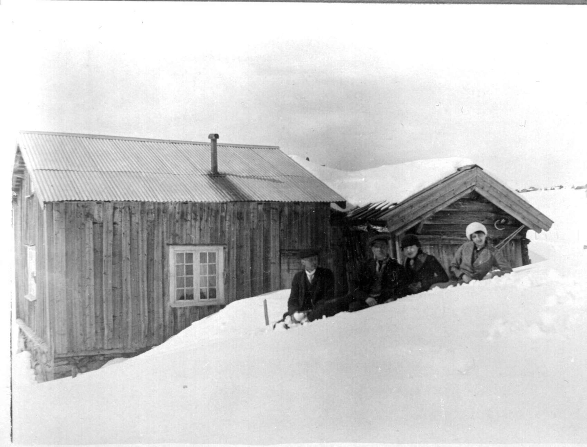 Repro: Hytte med fire personer i snøen utenfor.