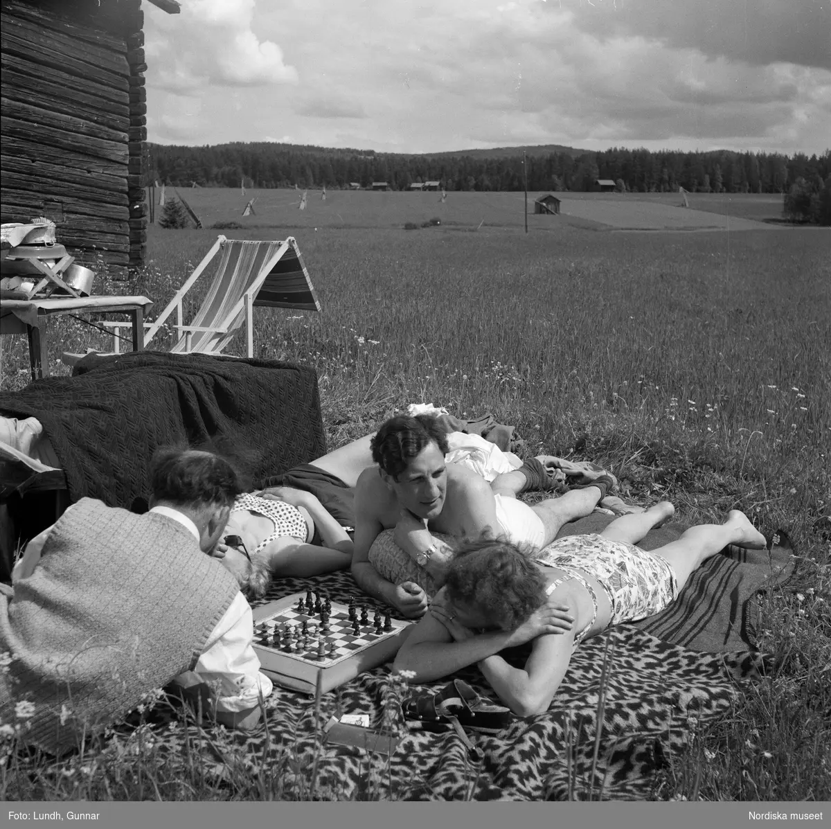 Motiv: (ingen anteckning) ;
Porträtt av en man författaren Frans G Bengtsson, en gärsgård, två kvinnor och två män ligger på marken och spelar schack vid en parkerad bil med husvagn, en kvinna står vid dörren till en husvagn, porträtt av en flicka som håller blommor.