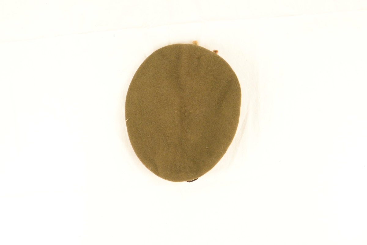 Grønn/brun beret med H7-merke i sølv.