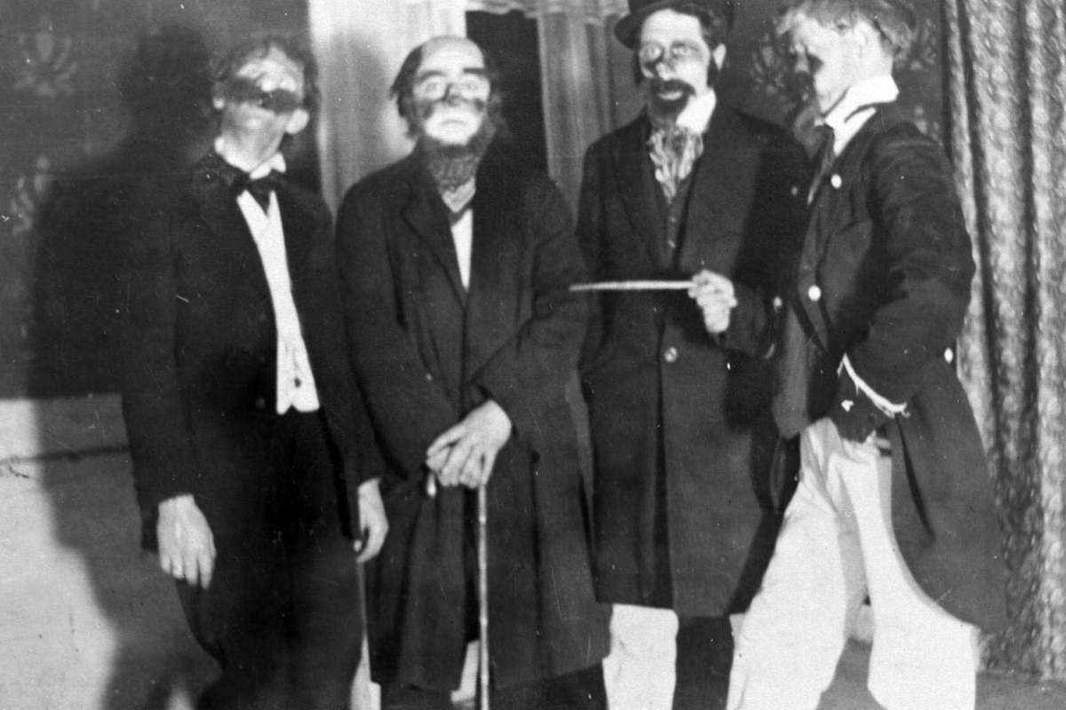 Gruppeportrett av fire menn utkledd i kostymer og med løsskjegg.