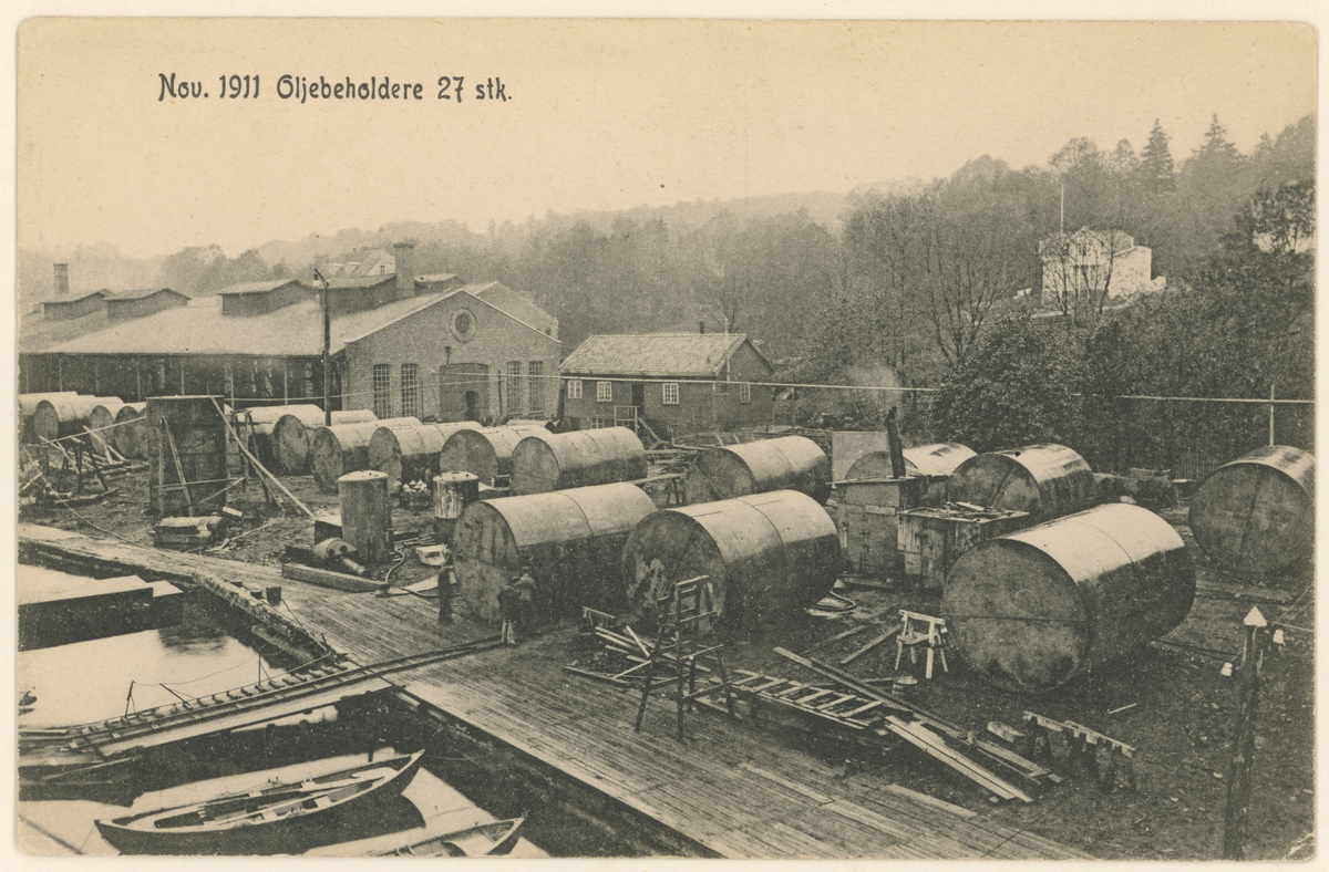 Fotograf har stått på flytedokk.
Detaljer: Værksteder, boliger, arbeidere, oljetanker.
Tekst:   "Nov. 1911 Oljebeholdere 27 stk." 