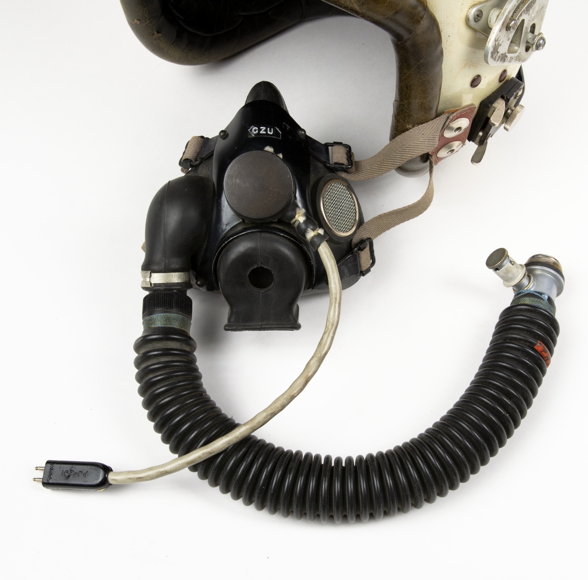 Flyghjälm av fransk modell med gasmask och visir. Hjälmen är har inredning och kant av läder. Till hjälmen hör en förvaringspåse och ett visirskydd av tyg.