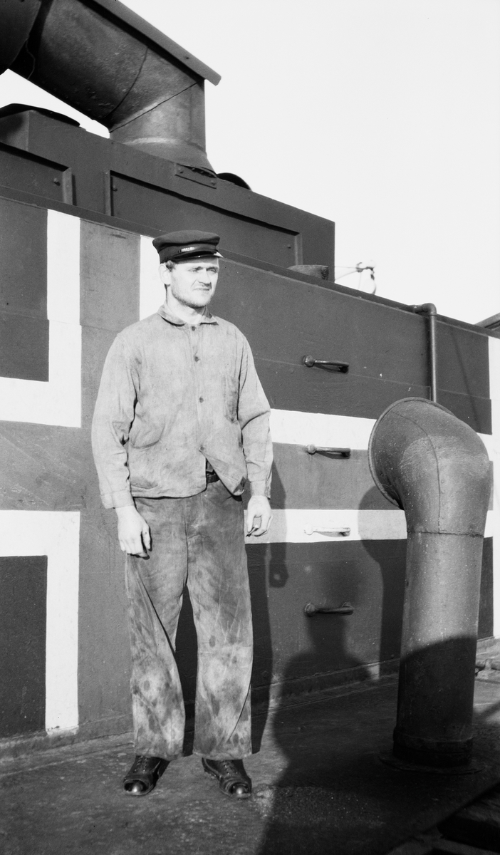 Sjømann foran nøytralitetsflagg på dekk om bord på D/S STORFOND.