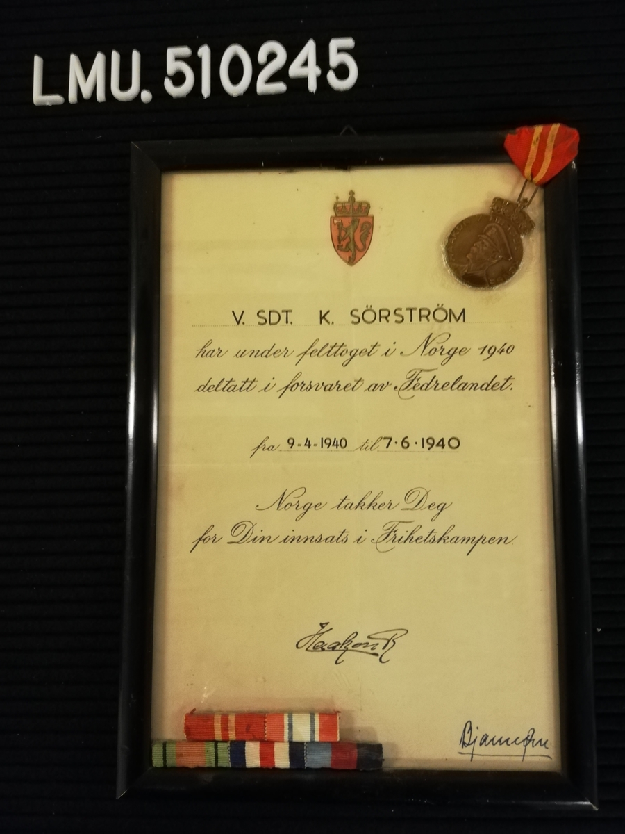 Diplom gitt til V.SDT. K. Sørstrøm for deltagelse i forsvaret av fedrelandet under felttoget i 1940.
Diplomet er signert av kong Haakon 7.
Diplomet er innrammet.