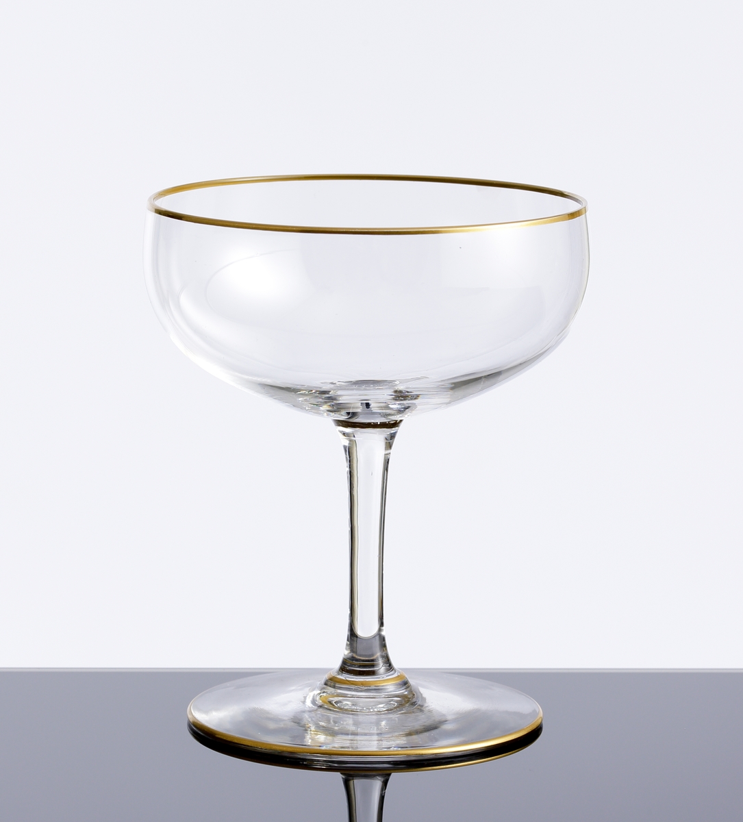 Champagnekupa med guldförgylld rand kring mynning och fot. Ofärgat klarglas.