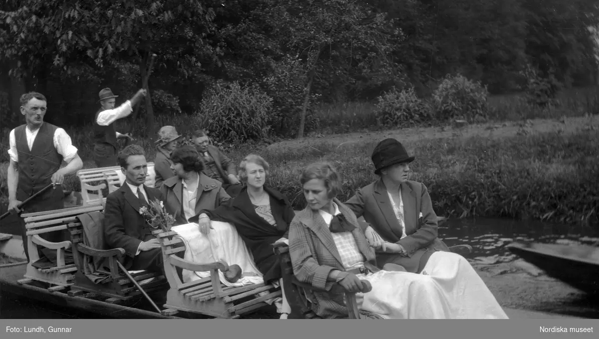 Motiv: Utlandet, Spreewald 92 - 101 ;
Kvinnor och män sitter i en båt, två kvinnor i folkdräkt. två kvinnor i folkdräkt står vid ett hus.