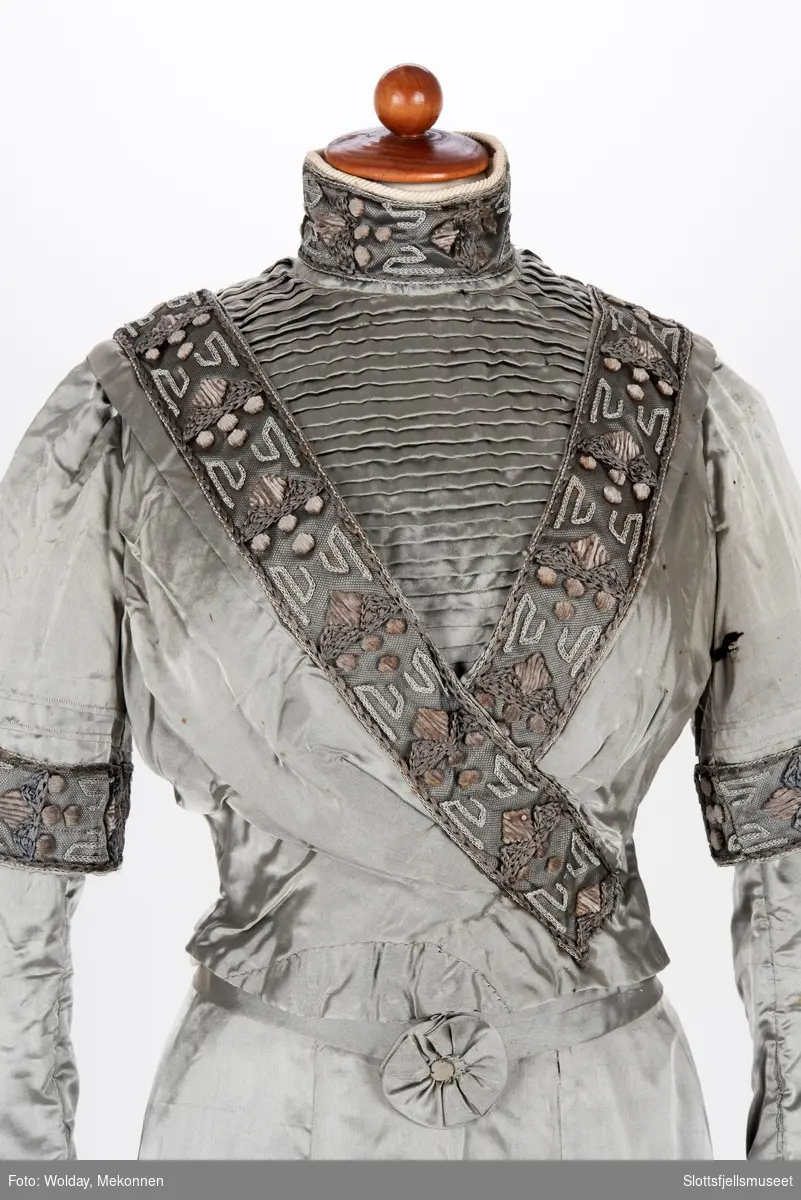 4 deler. Blank silke med dekor av bånd og sølvtråder på livet.