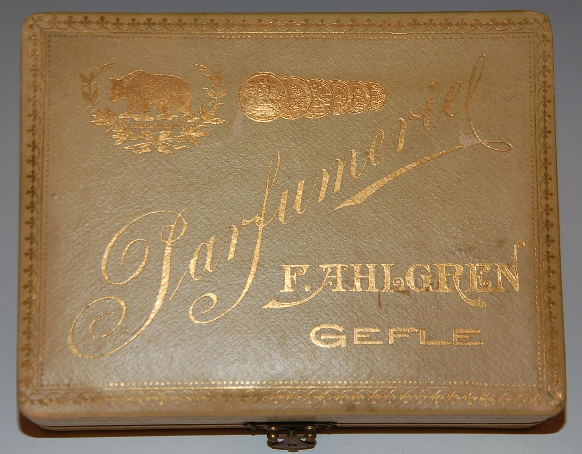 Etui med tre parfymflaskor.
På locket text i guld:
"Parfymeriet 
F. Ahlgren
Gefle"