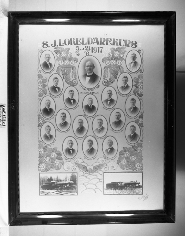 Tavla med porträttsamling eller kollage i brun glasad träram. Porträtten visar kursdeltagare och ledare vid SJ:s lokeldarkurs i Örebro 5/5 till 21/6 1917.