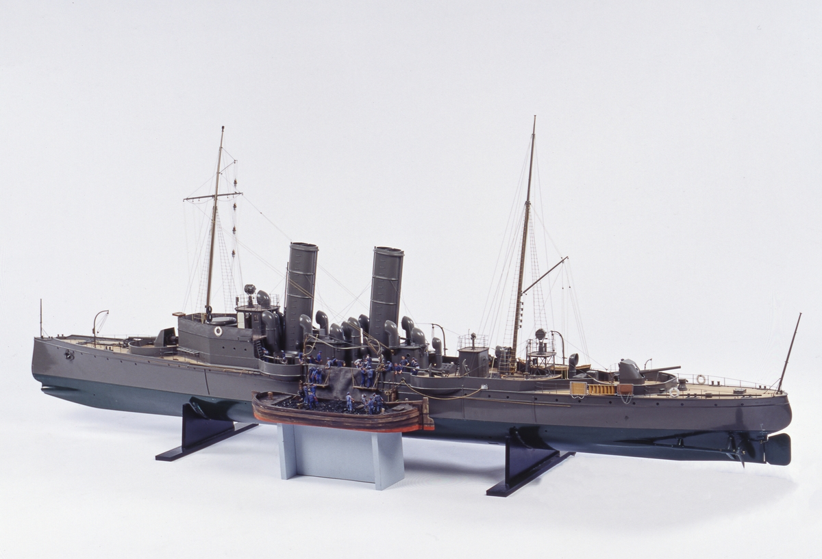 Fartygsmodell, torpedkryssaren Psilander, skala 1/32. Byggd av hoplimmat virke och sedan urskölpt. Undervattenskropp grönmålad, övervattenskropp och överbyggnad gråmålade. Ribbdäck. 2 propellrar. Rigg med stående och löpande gods. 2 st. 12 cm:s kanoner, 4 st. 57 m/m kanoner. Till skeppet hör flera mindre båtar:
En slup, 8-huggare med 8 st åror, 2 st. båtshakar och roder med rorkult (se bilder).
En slup,  4-huggare med 4 st åror, 2 st. båtshakar och roder med skädda.
1 joll för 4 åror med 4 st åror, 1 st båtshake och roder med rorkult.
1 ångslup med 2 åror och 2 båtshakar.
2 st. fallrep
2 st. ankare.
Flaggspel och gösstake utan flaggor. Vimpel å stortoppen. Skrå i form av 2 mässingspelare.
Längd: ö.a.: 226 cm Bredd: 24.2 cm Höjd utan skrå: 80 cm (stormasten).