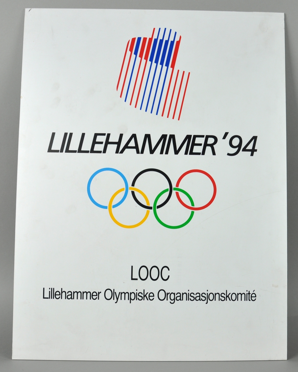 Skilt av papp som viser en tidlig versjon av logoen for LOOC (Organisasjonskomiteen for vinter-OL på Lillehammer), med nordlyssymbolet opp-ned.