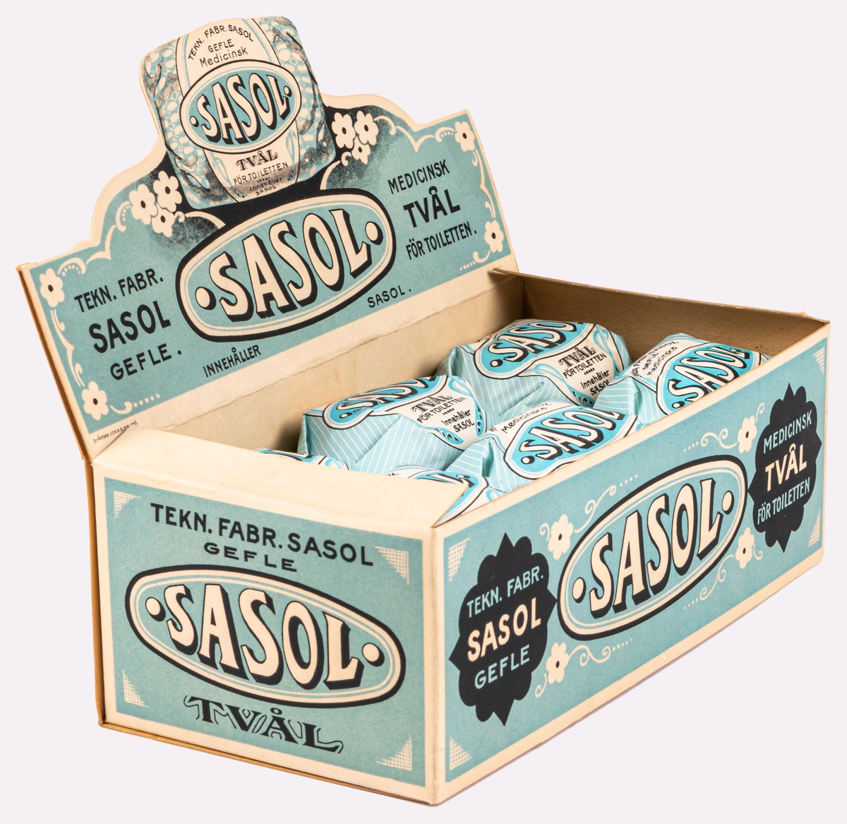 Ask med 11 medicinska tvålar, av märket Sasol. Tvålarna paketerade i papper. Locket till asken kan vikas upp så att asken kan användas för skyltställ.